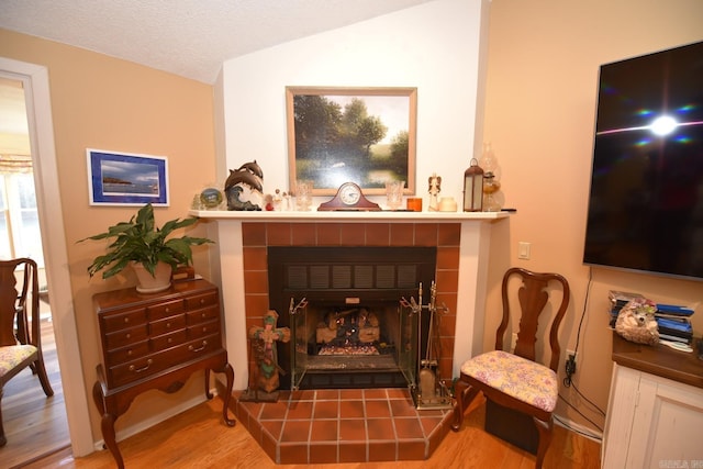 room details with a tiled fireplace, a textured ceiling, and wood finished floors