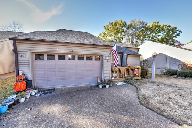 ranch-style home featuring aphalt driveway, a garage, and roof with shingles