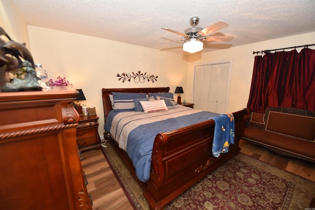 bedroom featuring ceiling fan, a closet, a textured ceiling, and wood finished floors