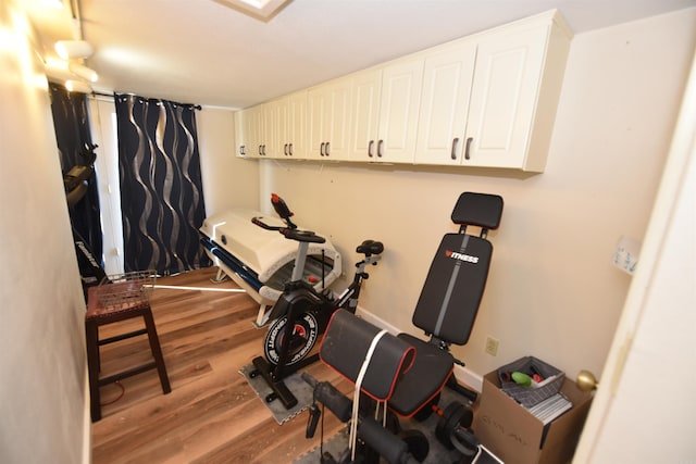 workout area featuring wood finished floors and baseboards