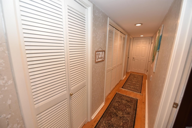 hallway featuring wood finished floors, baseboards, and a textured wall