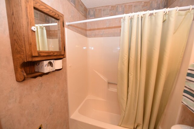 bathroom featuring a textured ceiling and shower / tub combo with curtain