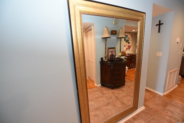 corridor with tile patterned flooring, visible vents, and baseboards