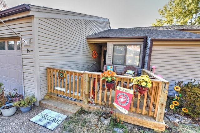 doorway to property with an attached garage and a shingled roof