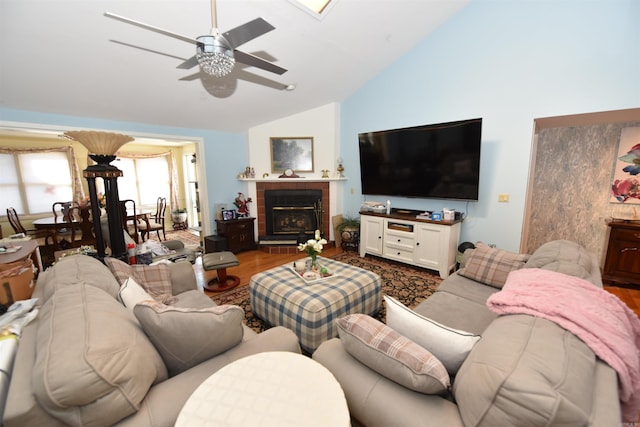 living room featuring lofted ceiling, a fireplace, wood finished floors, and a ceiling fan