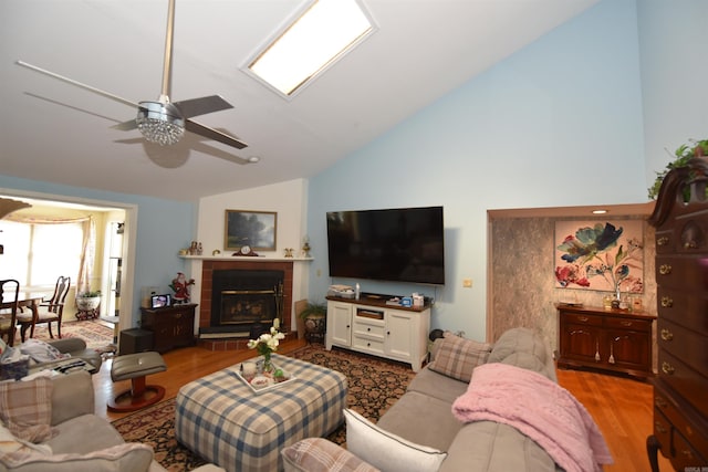 living room featuring a tile fireplace, high vaulted ceiling, a ceiling fan, and wood finished floors