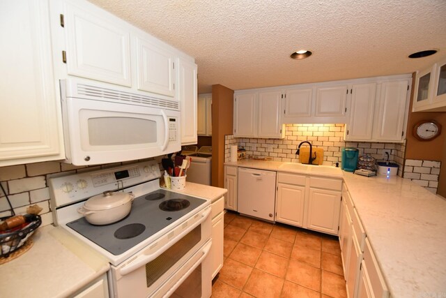 kitchen with a sink, white cabinetry, white appliances, light tile patterned flooring, and light countertops