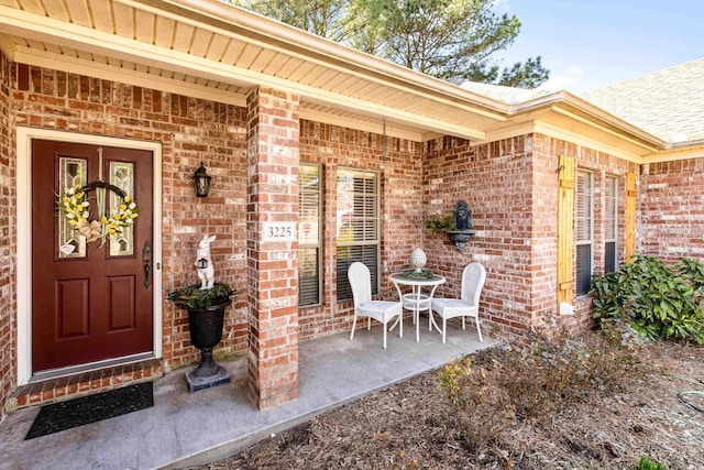 entrance to property with brick siding and a patio