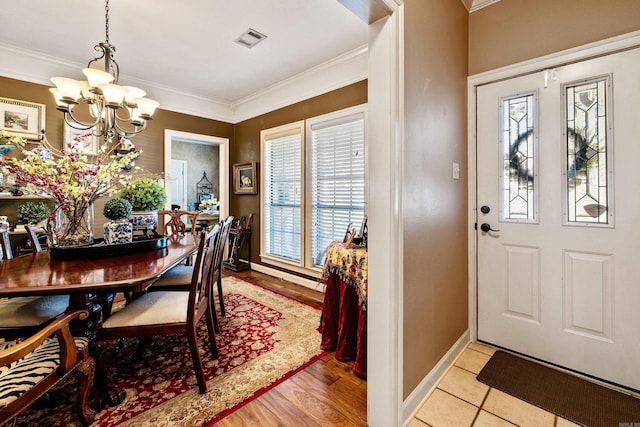 dining area featuring visible vents, baseboards, crown molding, and an inviting chandelier