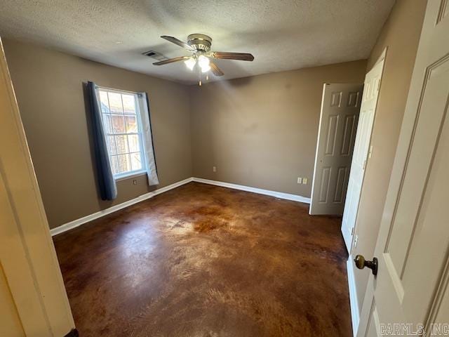 spare room featuring finished concrete floors, a textured ceiling, baseboards, and a ceiling fan