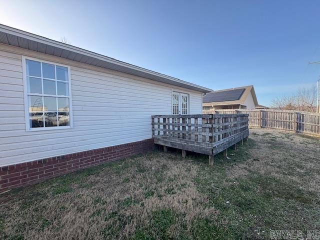 exterior space with a lawn, a wooden deck, and fence