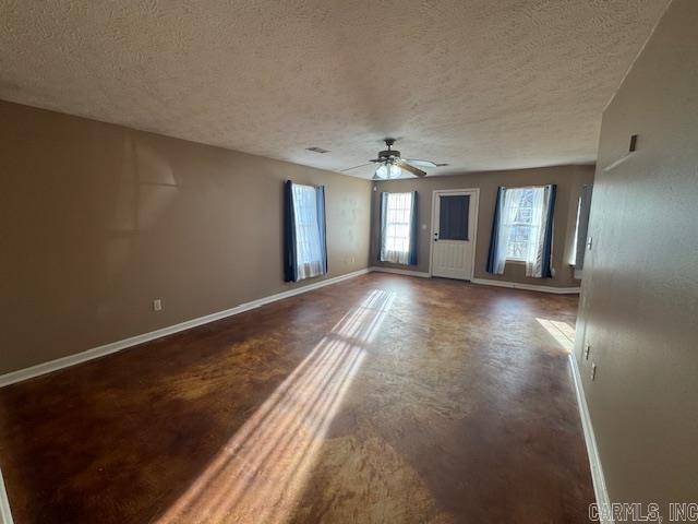 unfurnished room featuring ceiling fan, a textured ceiling, concrete flooring, and baseboards