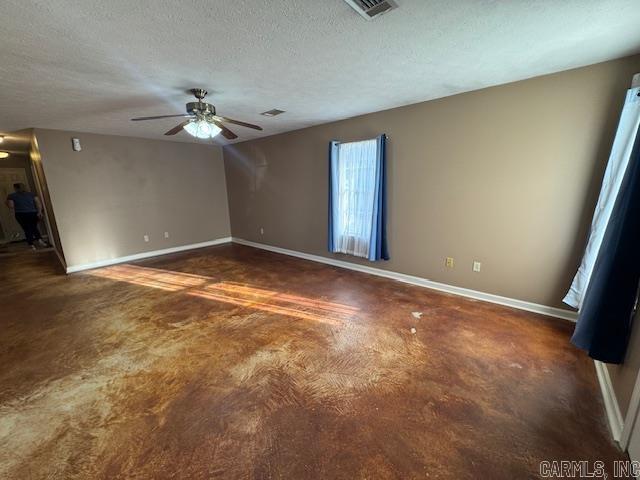 spare room featuring visible vents, baseboards, a textured ceiling, and a ceiling fan