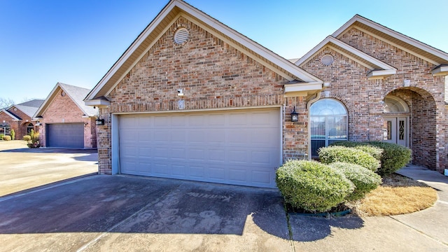 view of front of house with driveway, brick siding, and an attached garage