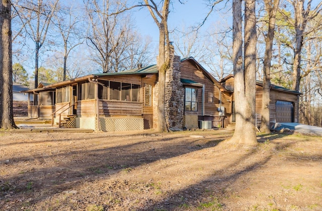 view of home's exterior with cooling unit, a chimney, and a sunroom