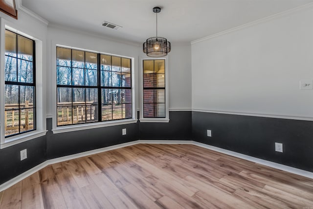 empty room with visible vents, crown molding, baseboards, and wood finished floors