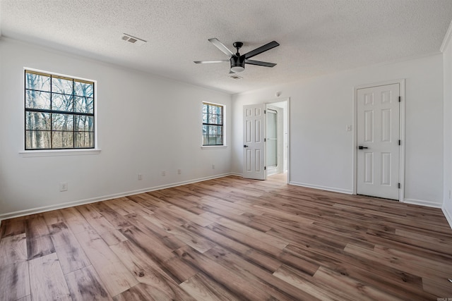 interior space with a textured ceiling, wood finished floors, visible vents, and ceiling fan