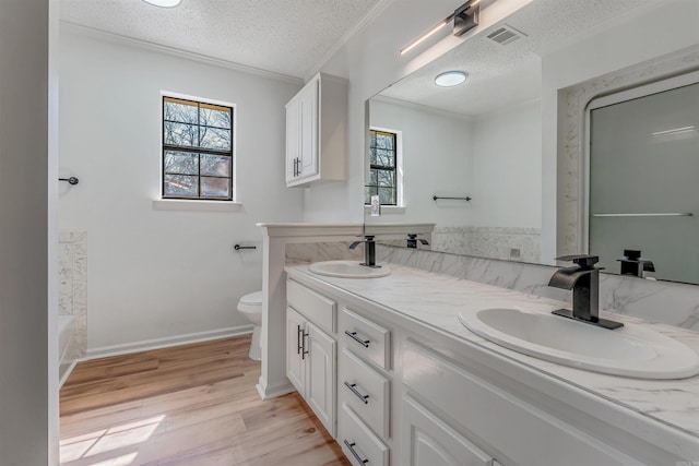 full bathroom featuring a textured ceiling, toilet, wood finished floors, and a sink