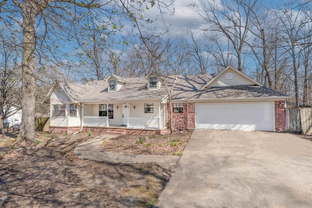 new england style home with driveway, fence, covered porch, a garage, and brick siding