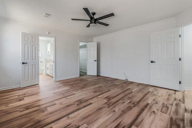 unfurnished bedroom with light wood-style floors, visible vents, ensuite bathroom, and a textured ceiling