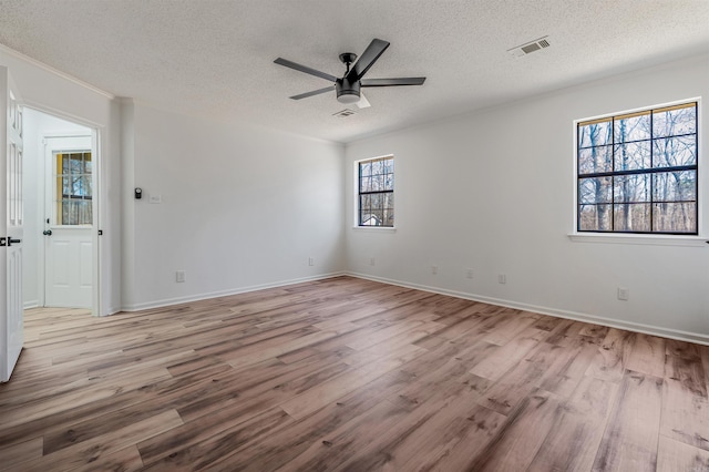 unfurnished room featuring visible vents, a textured ceiling, wood finished floors, and a ceiling fan