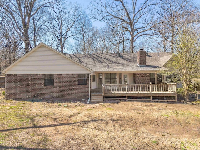 rear view of property featuring brick siding, a deck, and a chimney