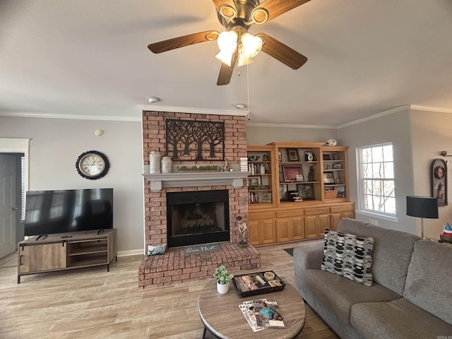 living room with a ceiling fan, baseboards, light wood-style flooring, crown molding, and a brick fireplace