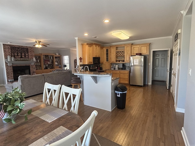 kitchen featuring a peninsula, a fireplace, freestanding refrigerator, glass insert cabinets, and black microwave