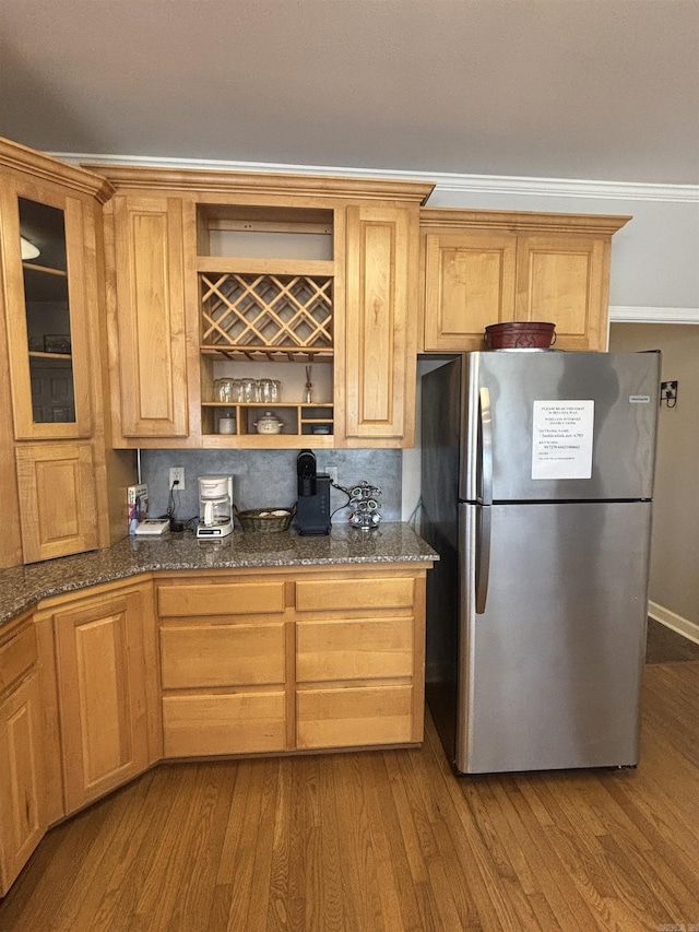 kitchen with open shelves, dark stone countertops, wood finished floors, freestanding refrigerator, and glass insert cabinets