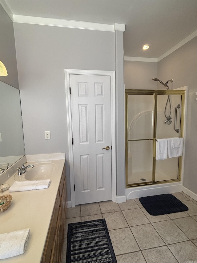 bathroom with double vanity, a sink, tile patterned flooring, a shower stall, and crown molding