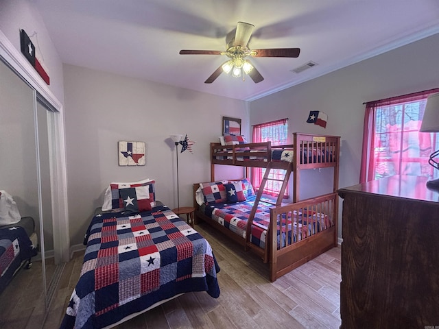 bedroom featuring wood finished floors, visible vents, a closet, and ceiling fan