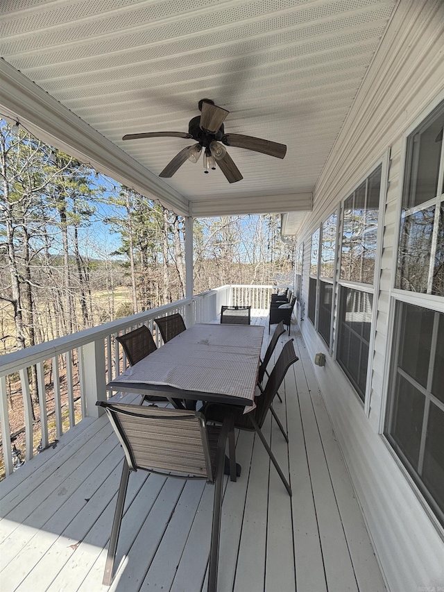 deck with outdoor dining area and a ceiling fan