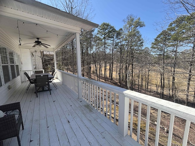 wooden terrace with outdoor dining area and ceiling fan