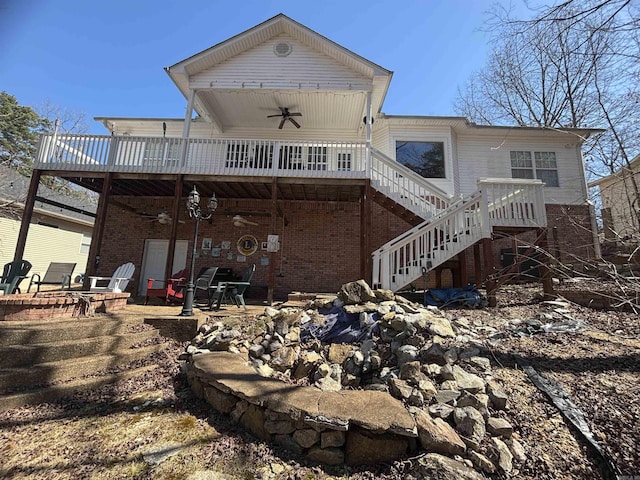 back of house with stairway, a patio area, brick siding, and a wooden deck