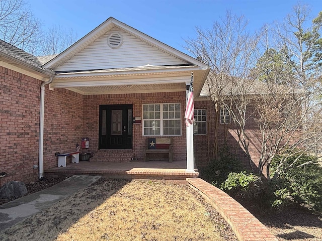 property entrance featuring brick siding and covered porch