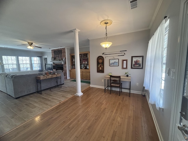 interior space with visible vents, wood finished floors, ornamental molding, and ornate columns