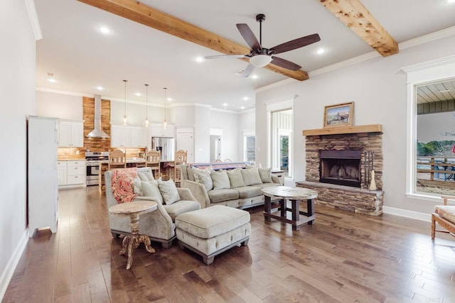 living room with beamed ceiling, a stone fireplace, dark wood finished floors, and crown molding