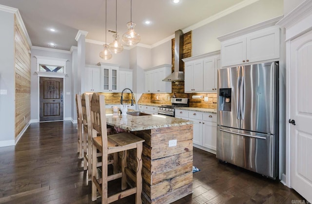 kitchen with a sink, wall chimney range hood, ornamental molding, and stainless steel appliances