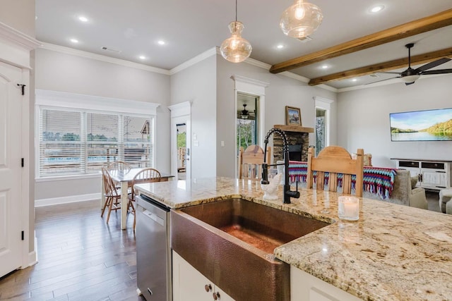 kitchen featuring ceiling fan, dishwasher, pendant lighting, a stone fireplace, and a sink