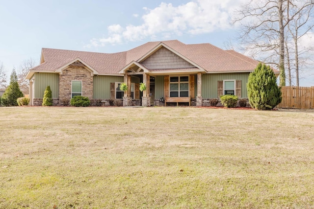 craftsman inspired home featuring a front lawn, fence, and roof with shingles