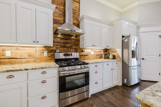 kitchen featuring appliances with stainless steel finishes, wall chimney exhaust hood, white cabinets, and ornamental molding