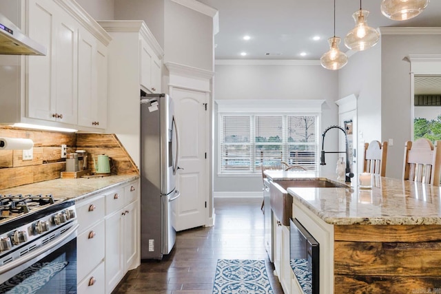 kitchen featuring decorative backsplash, under cabinet range hood, crown molding, and appliances with stainless steel finishes