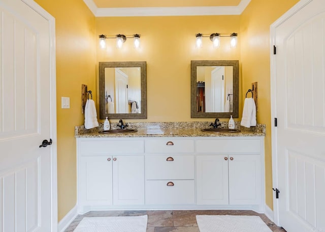 bathroom featuring a sink, baseboards, ornamental molding, and double vanity