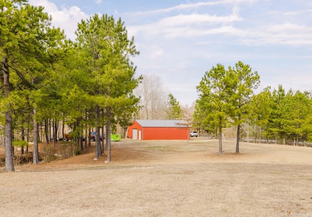 view of yard with driveway, an outdoor structure, a garage, and a pole building