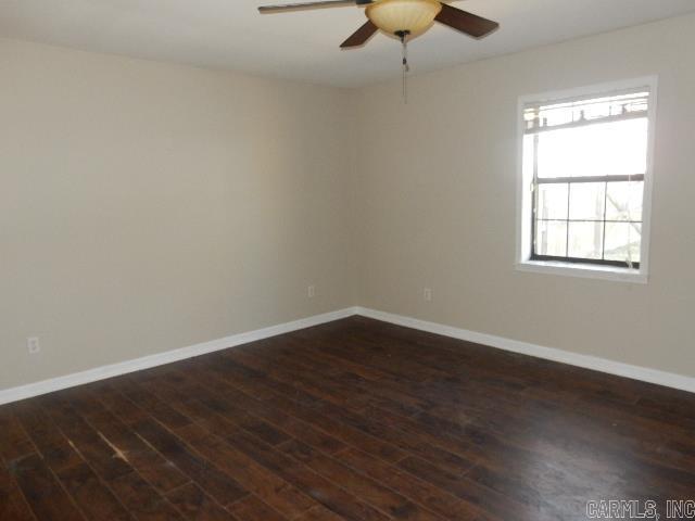 empty room with ceiling fan, baseboards, and dark wood finished floors