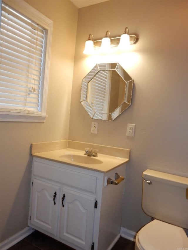 half bath featuring tile patterned flooring, toilet, vanity, and baseboards