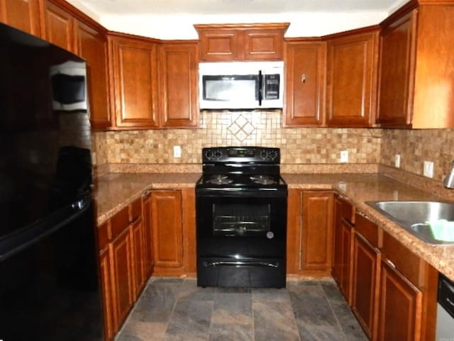 kitchen featuring decorative backsplash, brown cabinets, black appliances, and a sink