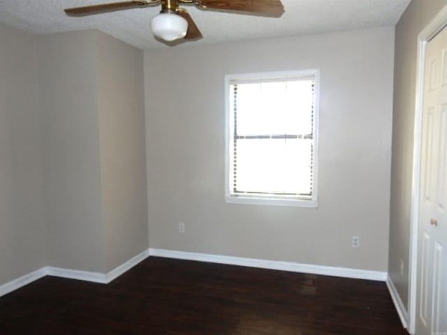 spare room featuring baseboards, a textured ceiling, dark wood finished floors, and a ceiling fan