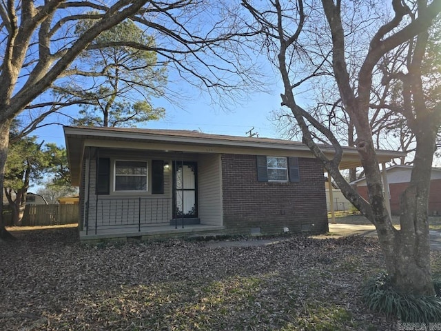 view of front facade with fence, covered porch, brick siding, and crawl space