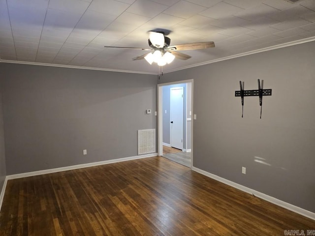 spare room with crown molding, wood finished floors, visible vents, and baseboards